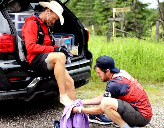 Shep taping Dave Proctor's feet at the tailgate of the support vehicle during Dave's cross-Canada record run