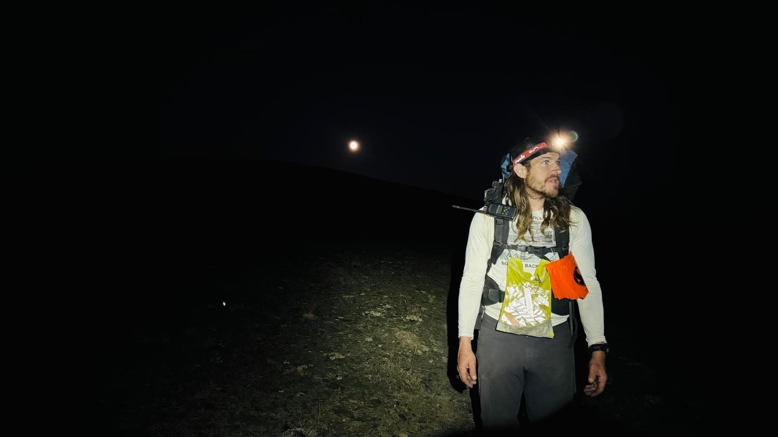 Shep marking a trail race course at night, headlamp on
